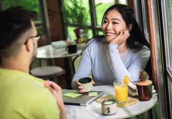 Couple sitting in a coffee shop talking and drinking coffee.