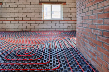 Installation of a heat flooring system in a country house under construction. Red tubes for floor...