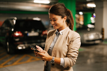 Businesswoman in suit unlocking car on parking. Beautiful woman talking to the phone.. - obrazy, fototapety, plakaty