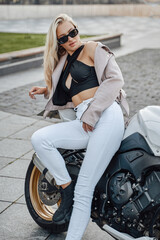 Obraz na płótnie Canvas Female motorcycle driver posing outdoors in city in daytime