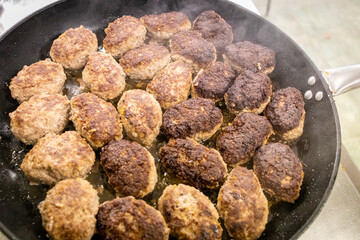 The mistress in the kitchen bake brown meatballs on the pan