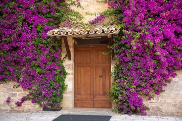 Foto auf Acrylglas Alte Türen Altes gemütliches Haus mit Holztür und lila Blumen