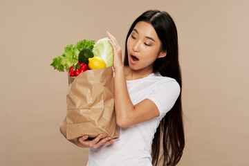 woman with a package of groceries healthy food snacks beige background housewife