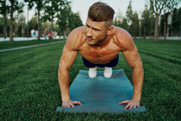 sports muscular man doing fitness crossfit in the park