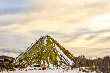 A waste rock dump (a waste heap) extracted from a copper mine against the background of a winter sky.
