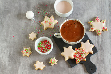 A cup of hot chocolate with Christmas star shape cookies on a table. Image from above.