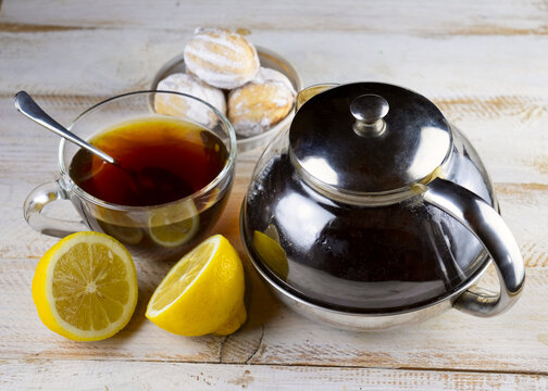 image of cookies, cups of tea, teapot with tea and lemon on a wooden table