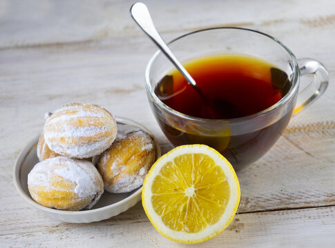 image of cookies, cups of tea, teapot with tea and lemon on a wooden table