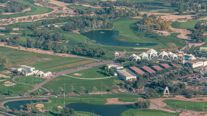 Fototapeta na wymiar Aerial view to Golf course with green lawn and lakes, villas and houses behind it timelapse.