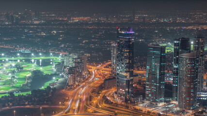 JLT skyscrapers with golf course near Sheikh Zayed Road aerial night timelapse. Residential buildings