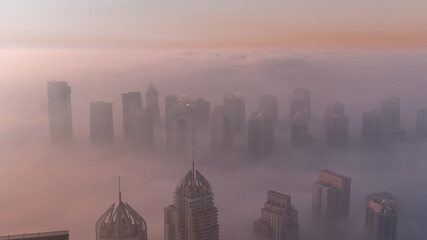 Fog covered JLT skyscrapers and marina towers near Sheikh Zayed Road aerial timelapse during sunrise. Residential buildings