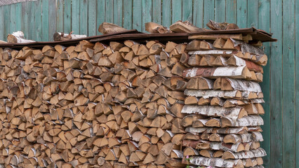 Firewoods stack at old fashioned wooden blue fence. Preparation for winter