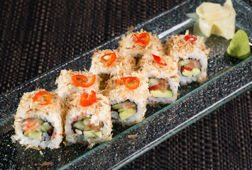 sushi roll with smoked salmon on a glass plate, close up photo on dark background
