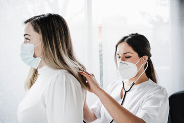 Female doctor checking patient with stethoscope during COVID-19