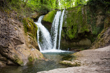 Fototapeta na wymiar Beautiful waterfall in green forest among trees