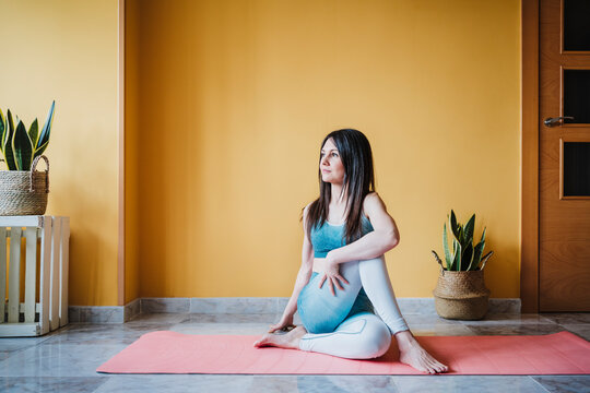 Woman in sportswear doing stretching on exercise mat at home