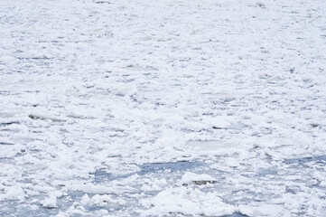 Snow-covered ice on the river during a snowfall. Winter texture.
