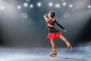Plakat Little skater rides on rings in red and black dress on ice arena