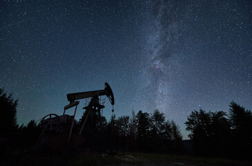 Silhouette of oil pump platform for mining production of petroleum in oilfield among forest at...