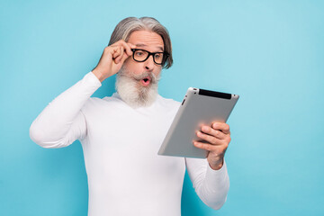 Portrait of attractive stunned grey-haired man using gadget reading new media post smm isolated...