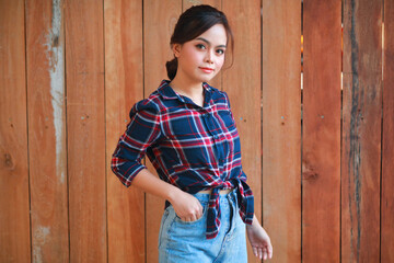 Portrait of cowgirl. Beautiful Young asian woman gardener in red plaid shirt at summer sunset.