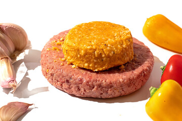 Big beef burger and cheese melt with yellow and red pepper and garlic on a white surface. Meat industry product. Cook craft.