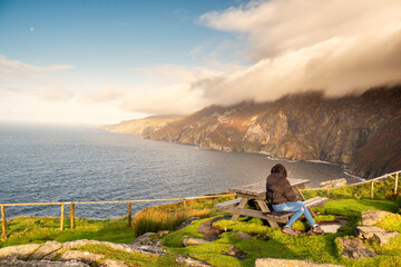 Teenager girl tourist enjoys amazing view on Slieve League cliff, county Donegal, Ireland. Stunning...