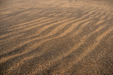 Amazing natural sand pattern made by wind and water on a sandy beach. Unique design for creative purpose. Design background. Random shapes on a dark and light sand surface