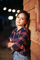 Portrait of cowgirl. Beautiful Young asian woman gardener in red plaid shirt at summer sunset.