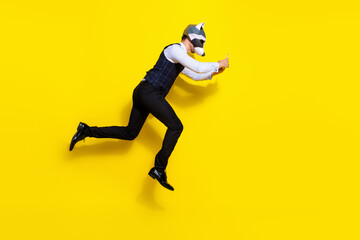 Fototapeta na wymiar Full body profile side photo of freaky racoon character guy jump run use device wear stylish vest isolated over yellow color background