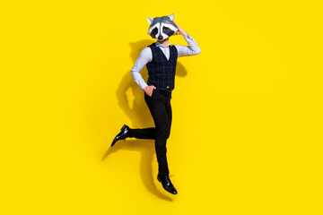 Full length photo of absurd bizarre guy jump touch racoon mask isolated over yellow shine color...