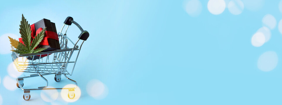 Marijuana sale banner. Shopping cart with gifts boxes and cannabis leaf. Christmas celebration with CBD products