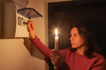 Woman turns ON automatic fuses during a electric power outage at home. Blackout city.