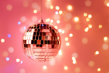 Fototapeta na wymiar Happy New Year party backdrop with Disco ball against pink color background and beautiful sparkling bokeh.