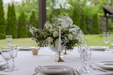 Table centerpiece with white and green floral arrangement in vase.