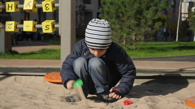 Little boy digging sand in sandpit with shovel on playground. Concept of child development, sports and education.