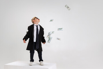 Portrait of emotional little boy, child businessman in huge jacket suit standing on big box isolated on white studio background.