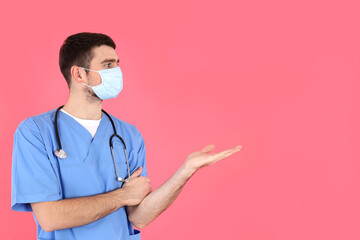 Young attractive male nurse on pink background