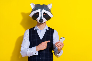 Photo of promoter guy hold telephone direct finger device novelty wear raccoon mask vest isolated yellow color background © deagreez