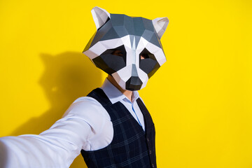 Photo of confident influencer guy hold camera take selfie wear raccoon mask vest isolated yellow color background