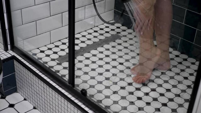 woman stands in shower with black and white tiles