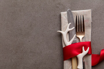 Festive Christmas table setting with cutlery wrapped in a red ribbon with an antler decoration
