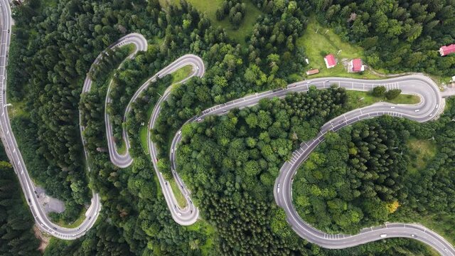 Overhead view of windy roads near the town of busteni in Transylvania, Romania with cars coming and going in the middle of a lush forest