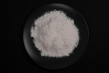Flour in a black plate on a black background.