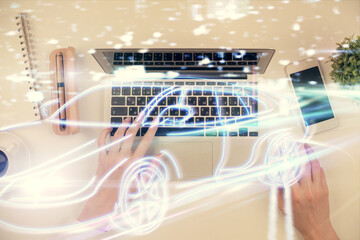 Double exposure of woman hands working on computer and car hologram drawing. Top View. Auto pilot concept.