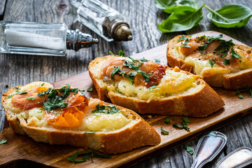 Tasty sandwiches - baked bread with mozzarella, salmon and parsley on wooden table
