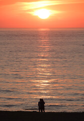 Fototapeta premium silhouette of 2 people at sunset