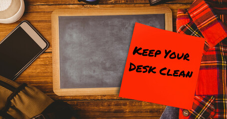 Image of keep your desk clean text on memo note over chalkboard on desk