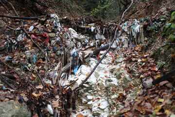 plastic and cloth abandoned for years in a creek - pollution of natural environment
