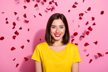 Photo of adorable sweet young woman wear yellow outfit roses petals falling smiling isolated pink color background